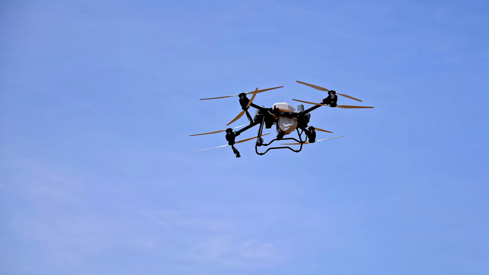 Industrial drone flying in clear blue sky. An agricultural drone equipped with multiple rotors is flying in the sky, used for crop monitoring, spraying, or farm management