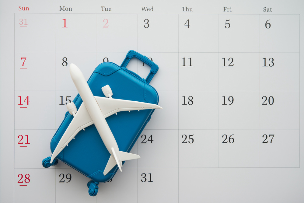 Airplane and suitcase on white calendar background. Travel holiday or annual leave travel period for relaxation concept. Period of paid time off (PTO) granted to employees by their employer